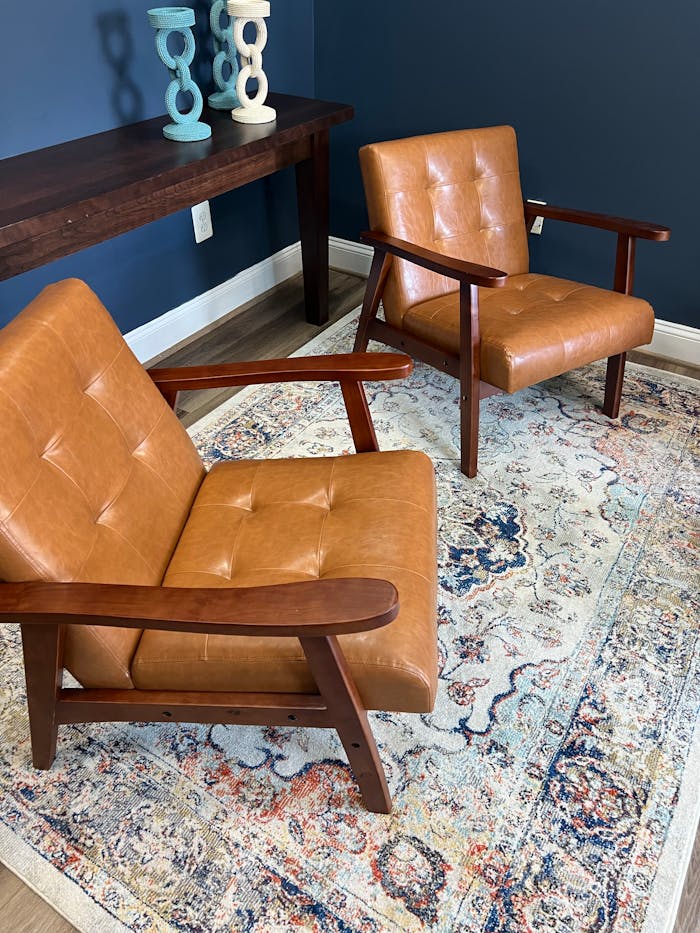 Two mid-century modern leather chairs on a patterned rug in a stylish living room.