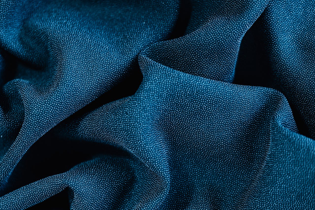 Detailed close-up of blue fabric showcasing rich texture and folds, perfect for textiles and fashion themes.