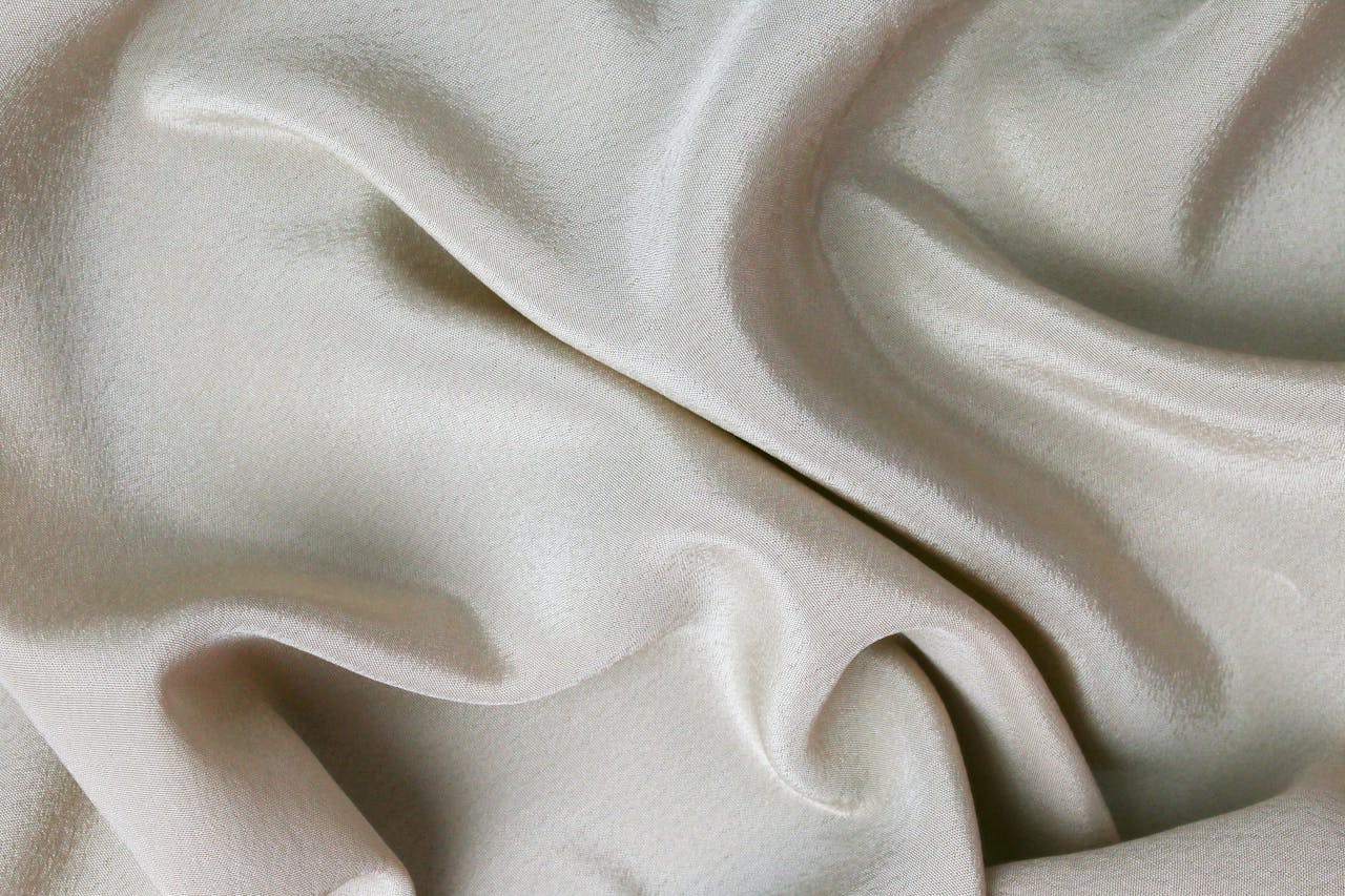 Close-up image of smooth, rippled cream silk fabric showcasing texture and elegance.